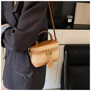 Detail of a retro straw woven box bag featuring tan leather trim and golden metal zippers