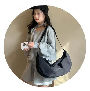 Detail view of large black nylon crescent tote bag worn by a model in casual grey set