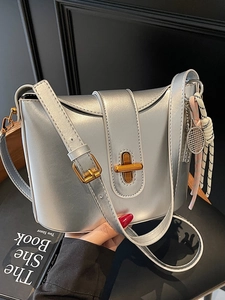 Minimalist silver bucket shoulder bag with gold twist lock and tennis racket pendant