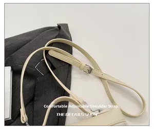 Detail of adjustable strap with silver buckle on beige textured leather shoulder bag
