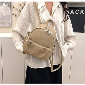 Detail showing high-quality lychee texture leather and silver zipper on beige small backpack