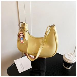 Detail of light yellow oil wax leather hobo bag with adjustable strap and cute charm