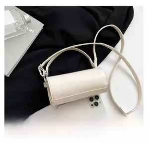 Mini cremeweiße Zylindertasche mit Schultergurt und Handy zum Größenvergleich