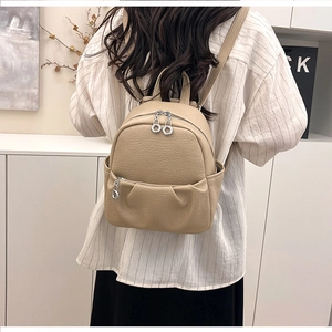 Detailed view of beige litchi pattern mini backpack with silver circular zipper pulls