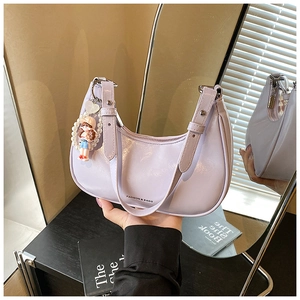 Sac croissant en cuir ciré mauve avec breloque perle et poupée dans un décor chic