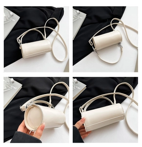 Detailansicht einer cremefarbenen Zylindertasche mit Tragegriffen und Schultergurt