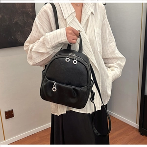 Detail of lychee pattern leather mini backpack featuring silver ring zippers and slim straps