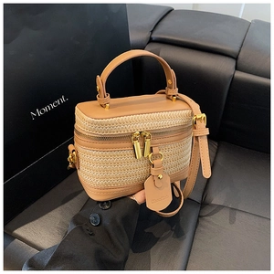 Detail of woven straw and brown PU leather box bag with gold double zipper closure