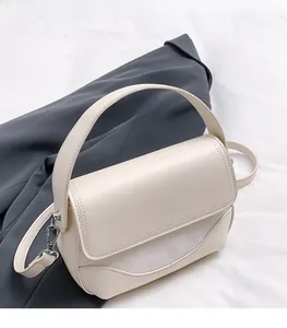 Detail of cream-colored PU saddle bag with metal logo and refined curved stitching