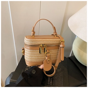 Detail of a woven box handbag with brown faux leather trim and golden double zippers