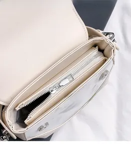 Detail view of beige saddle bag interior with silver zipper and magnetic flap closure