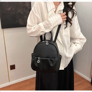 Close-up of litchi texture black leather mini backpack featuring metal ring pullers