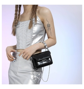 Detail of black patent leather mini bag with decorative silver heart chain handle and strap
