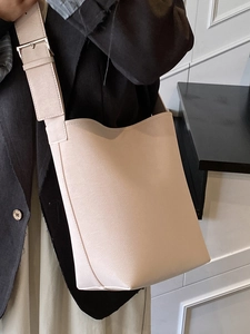 Sac seau minimaliste en similicuir beige pour femme avec large bandoulière et boucle argent