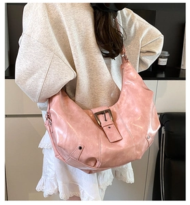 Detail of pink vintage hobo bag showing glossy leather texture and metal buckle on the strap
