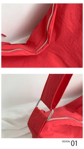 Detailed close-up of red nylon tote bag with smooth silver metal zipper and shoulder strap link