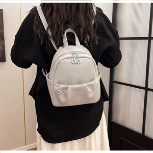 Detail of light grey lychee textured PU leather backpack with silver ring zippers