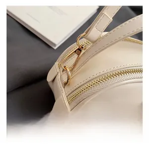 Detail of high-quality golden metal hooks and hardware on minimalist cream leather bag