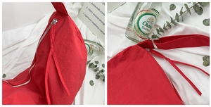 Close-up of vibrant red fabric tote bag showing silver metal zipper and shoulder strap