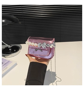 Close-up of metallic pink mini square bag with pearl handle and silver chain strap