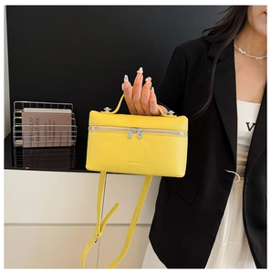 Detail of yellow lychee texture leather handbag with silver zippers and top handle