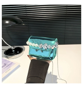 Detail of teal metallic mini bag with pearl trim and heart charms on a book background