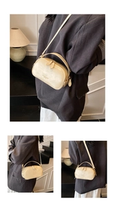 Detail view of cream oil wax leather crossbody bag featuring dual zippers and metal logos