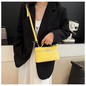 Detail of yellow lychee texture leather handbag with silver zipper and slim shoulder strap