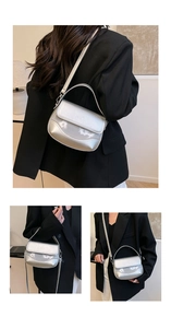 Detail view of silver metallic shoulder bag with top handle and sleek flap closure design