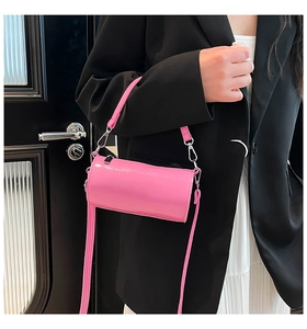 Rosafarbene Zylindertasche aus Lackleder kombiniert mit schwarzem Blazer und Rock