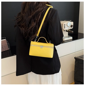 Macro detail of yellow litchi pattern leather handbag with silver zipper and top handle