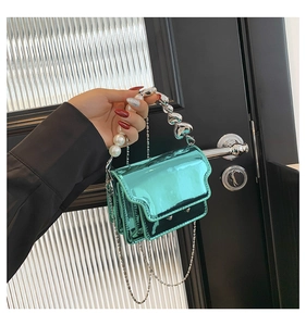 Detail of metallic green mini bag with pearl handle and silver heart metal charm