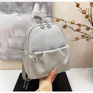 Macro view of grey lychee pattern leather backpack with silver metal ring zippers
