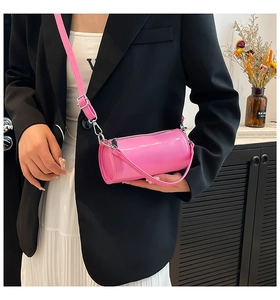 Detailansicht der glänzenden rosa Zylindertasche mit Schultergurt an einem Model