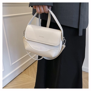Close-up of off-white faux leather saddle bag with ZHCNMA logo and silver hardware