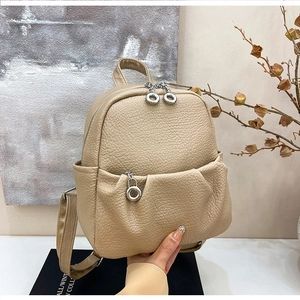 Close-up of beige lychee grain leather mini backpack with silver circular zippers