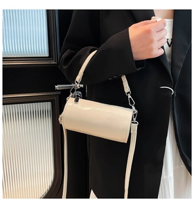 Detail einer cremefarbenen Zylindertasche aus Ölwachsleder mit silbernen Metallteilen