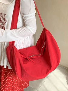 Minimalist large red half-moon hobo bag with wide shoulder strap and metal zipper