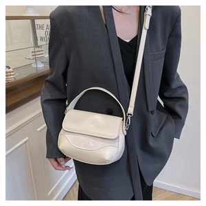 Detail of cream white leather saddle bag with brand logo and adjustable shoulder strap