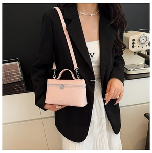 Detail of light pink lychee texture leather crossbody bag shown on a model waist