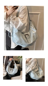 Detail of light blue patent leather crescent bag with silver buckle and pleated texture