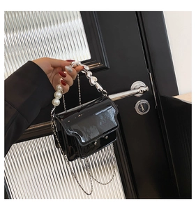 Detail of glossy black patent leather mini bag with pearl and heart-shaped beaded handle