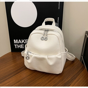 Close-up of white lychee pattern leather backpack with silver ring zippers on wood table