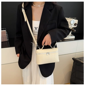 Detail view of cream lychee texture leather handbag with silver double zippers and handle