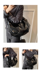 Detail of black glossy crinkled leather tote bag featuring metal buckle and punk studs
