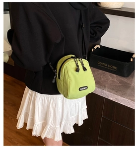 Detail of neon green nylon crossbody bag with Lucky label worn by a model