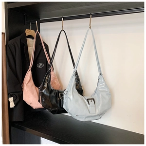 Close-up of stylish glossy hobo bags in pink, black, and blue with buckle detail