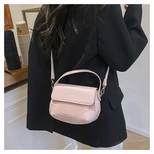 Pale pink leather saddle bag with silver ZKEAKIA metal logo worn over a black blazer