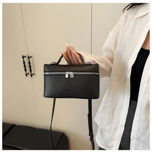 Detail view of black lychee grain leather crossbody bag with silver zipper and handle
