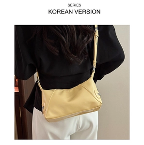 Close-up of a minimalist pale yellow crescent tote bag with an adjustable strap and zip